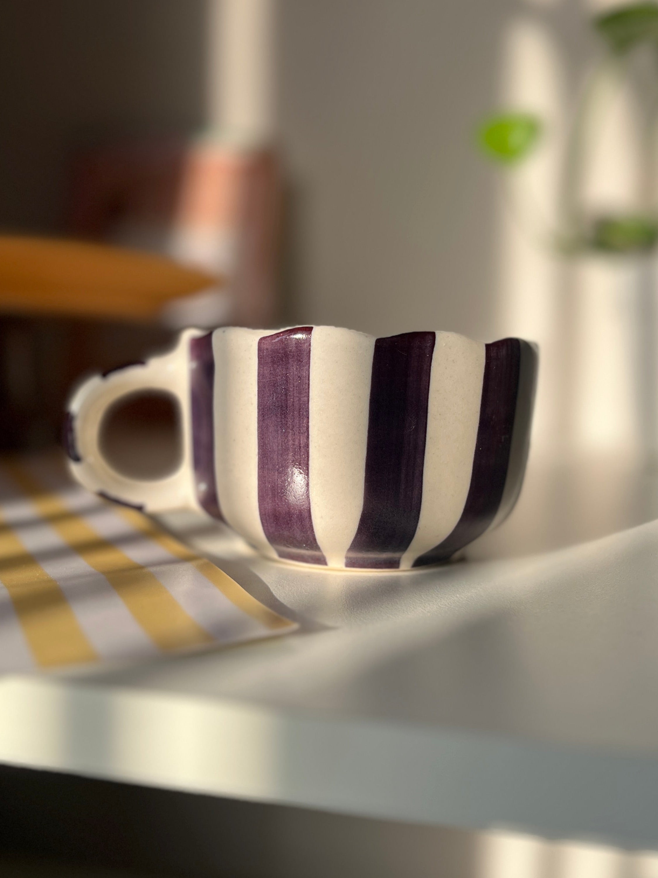 Striped ceramic cup on a table with a blurred background. purple, blackcurrant color. 