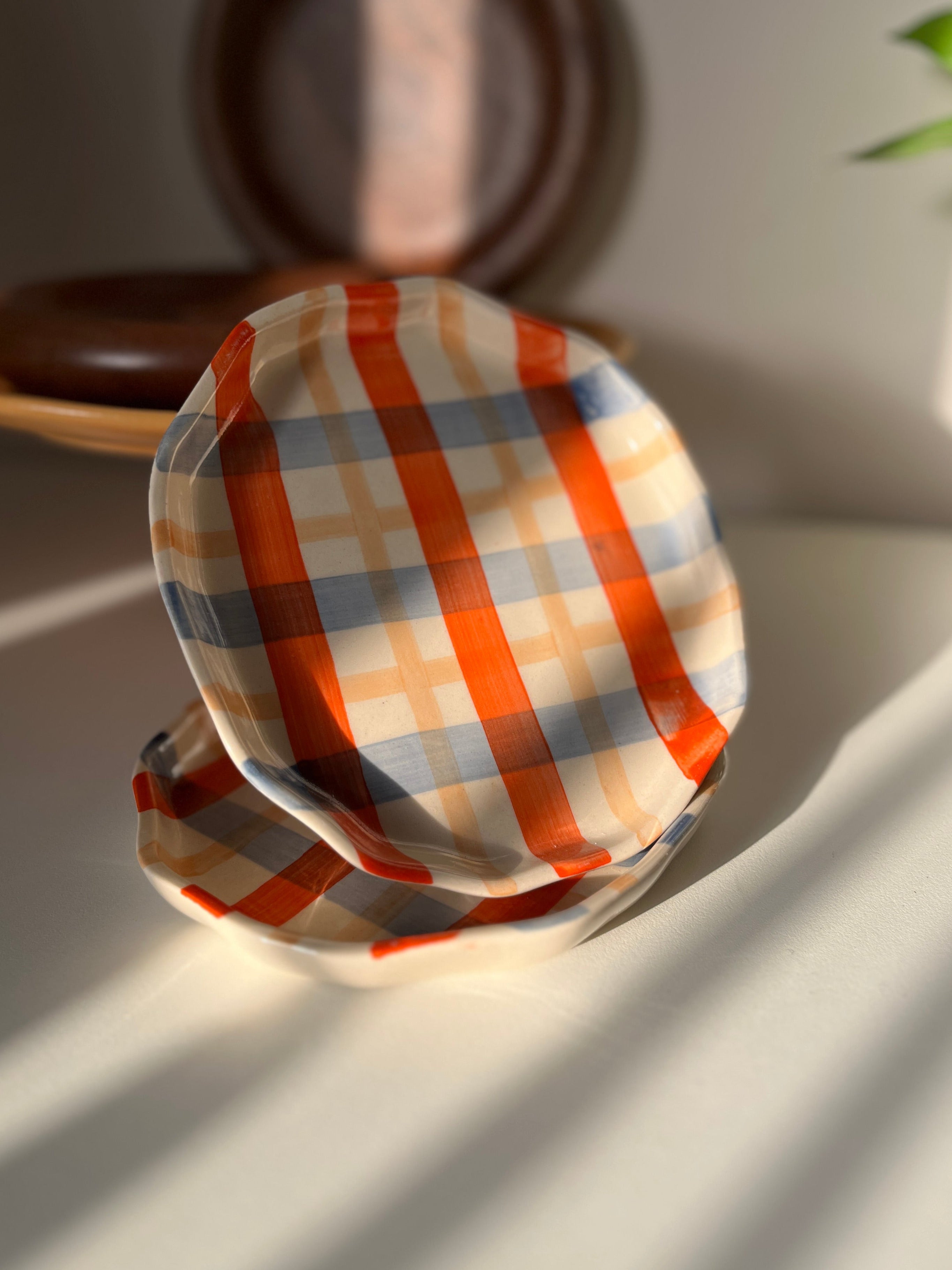 Stack of checkered ceramic plates on a light surface with a blurred background