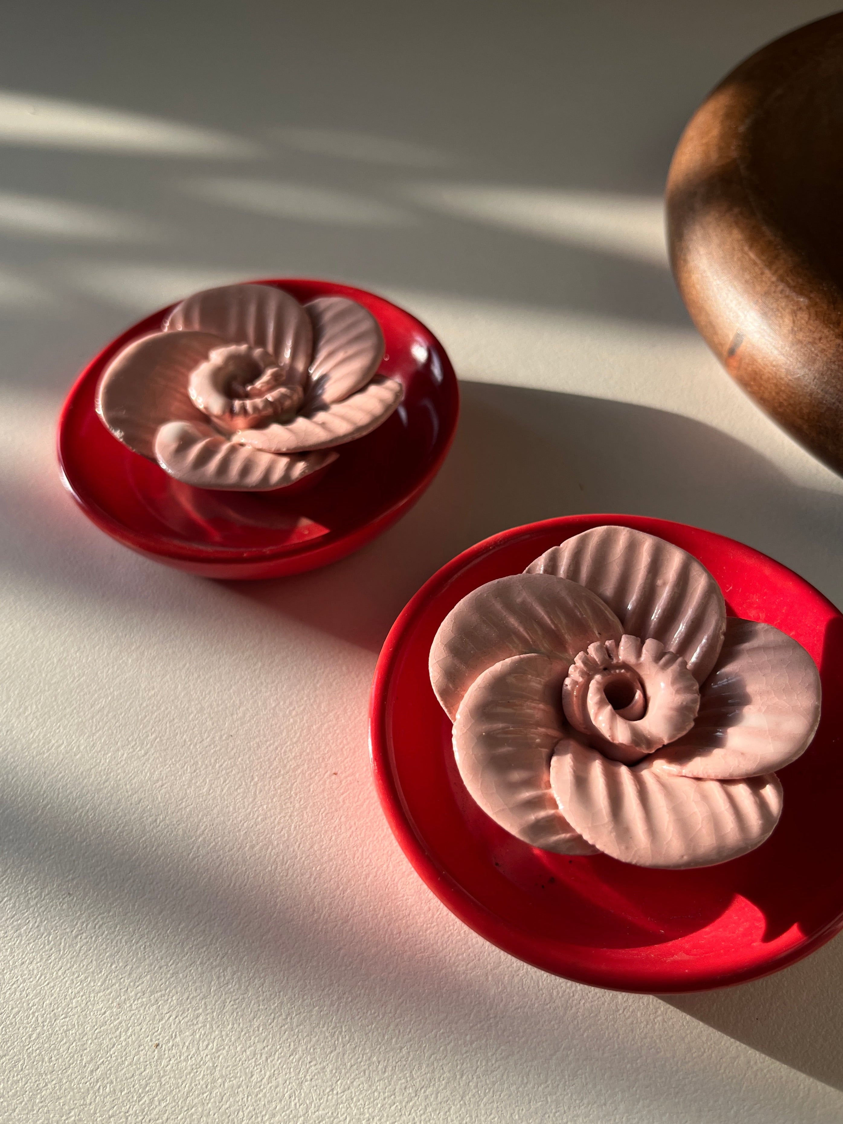Decorative items with red bases and metallic top designs on a light background