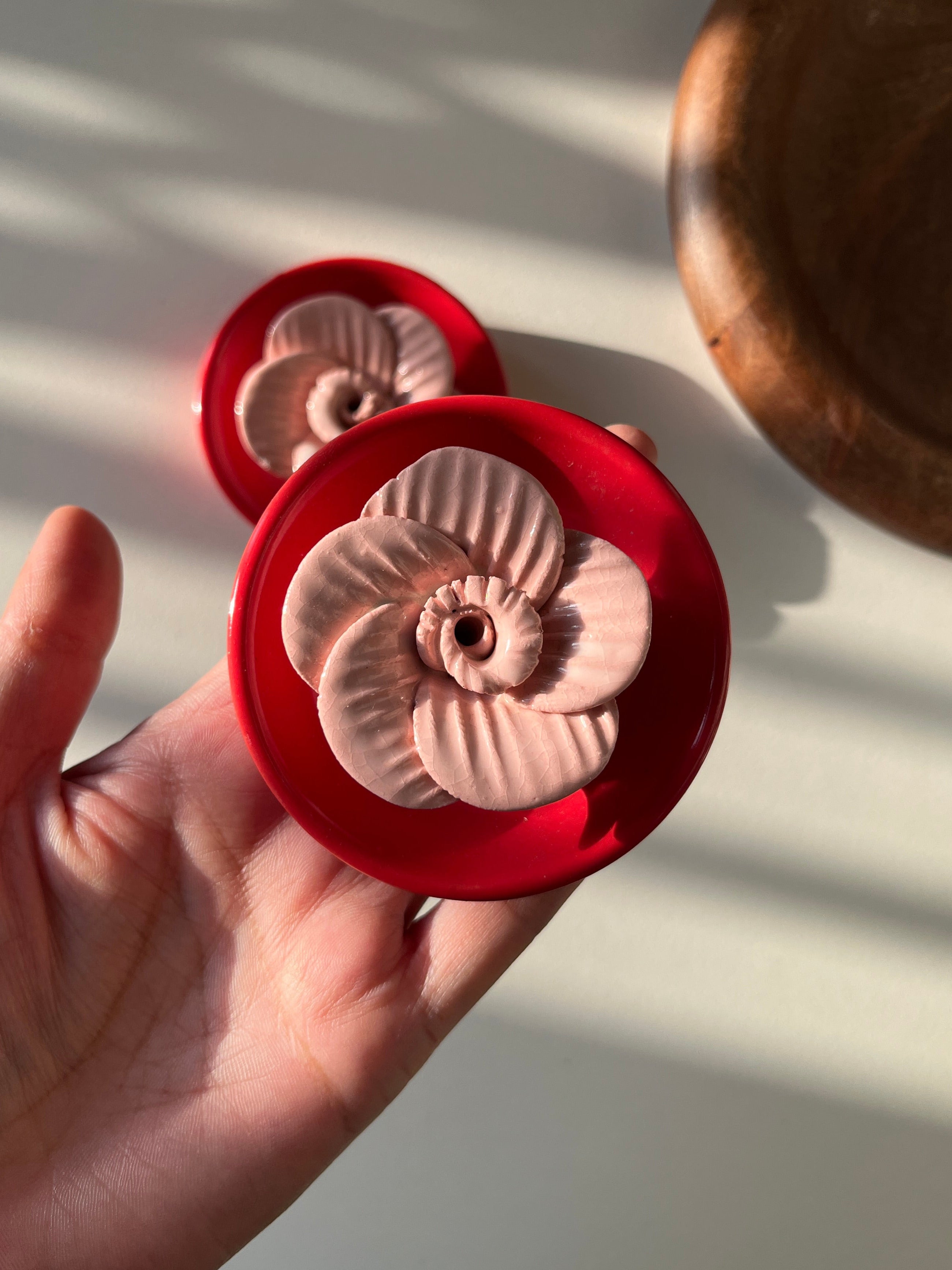 Hand holding a red decorative item with a white background