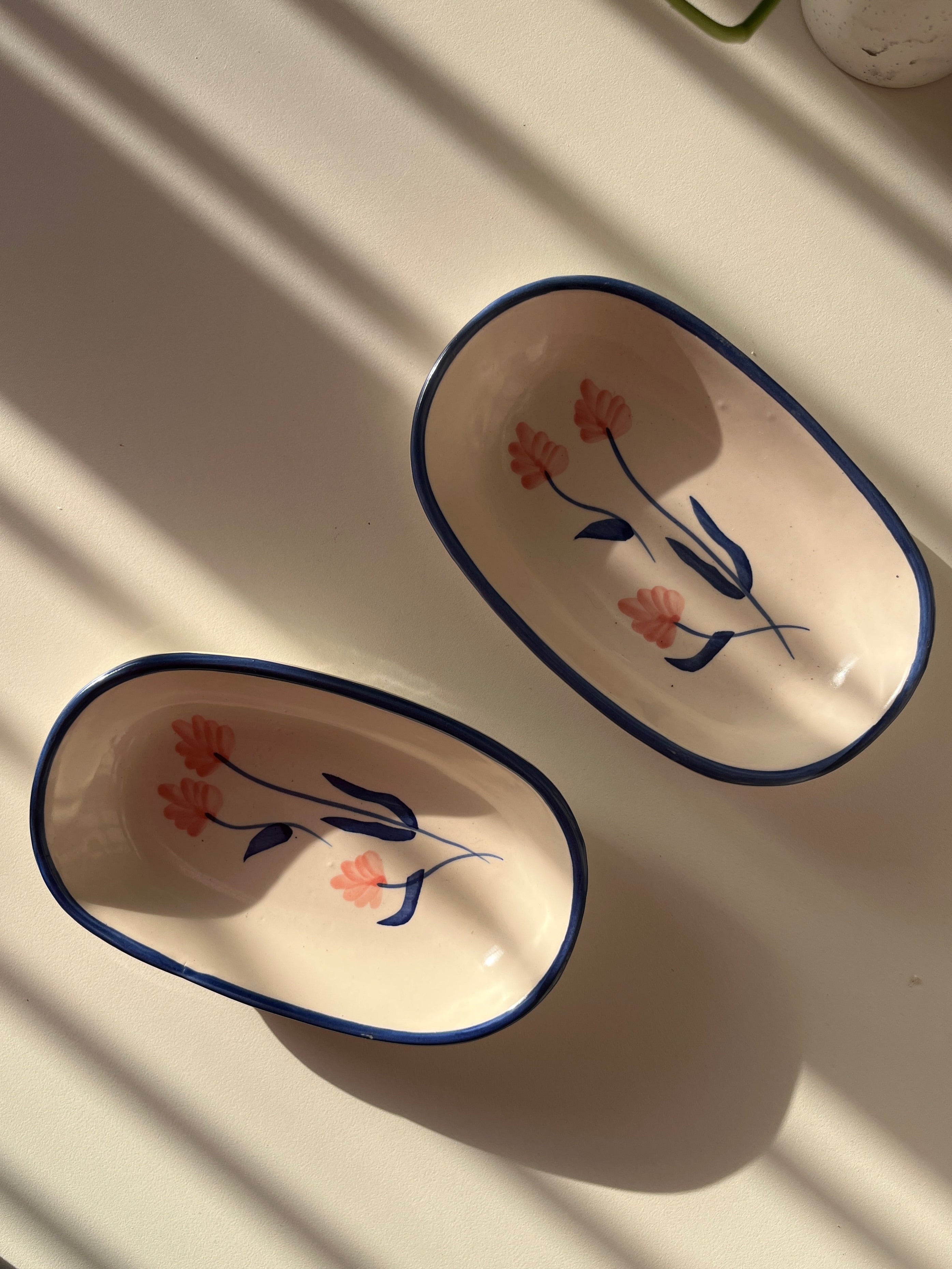 Two oval ceramic dishes with floral designs on a white surface.