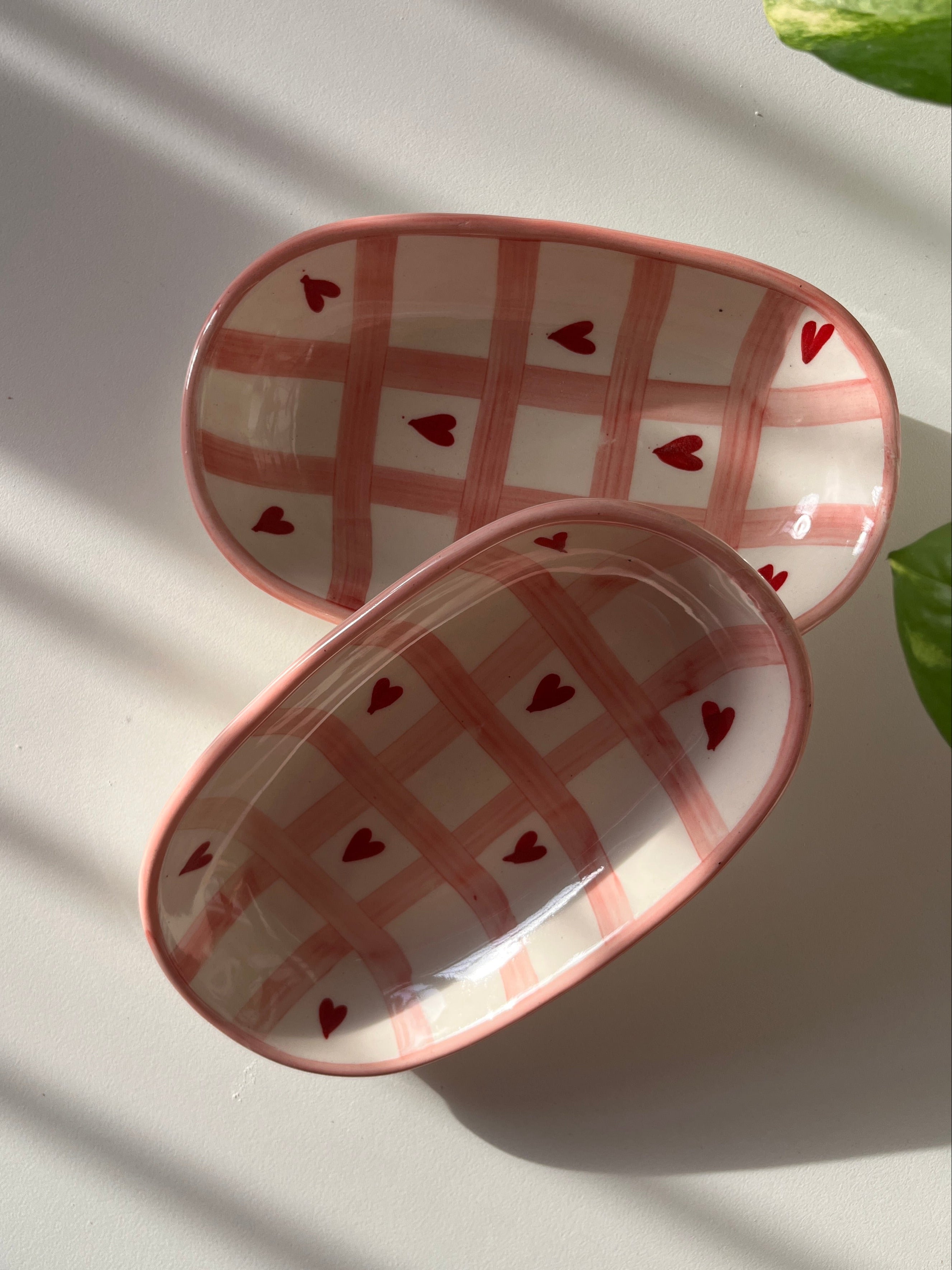 Two small ceramic dishes with heart patterns on a white surface.