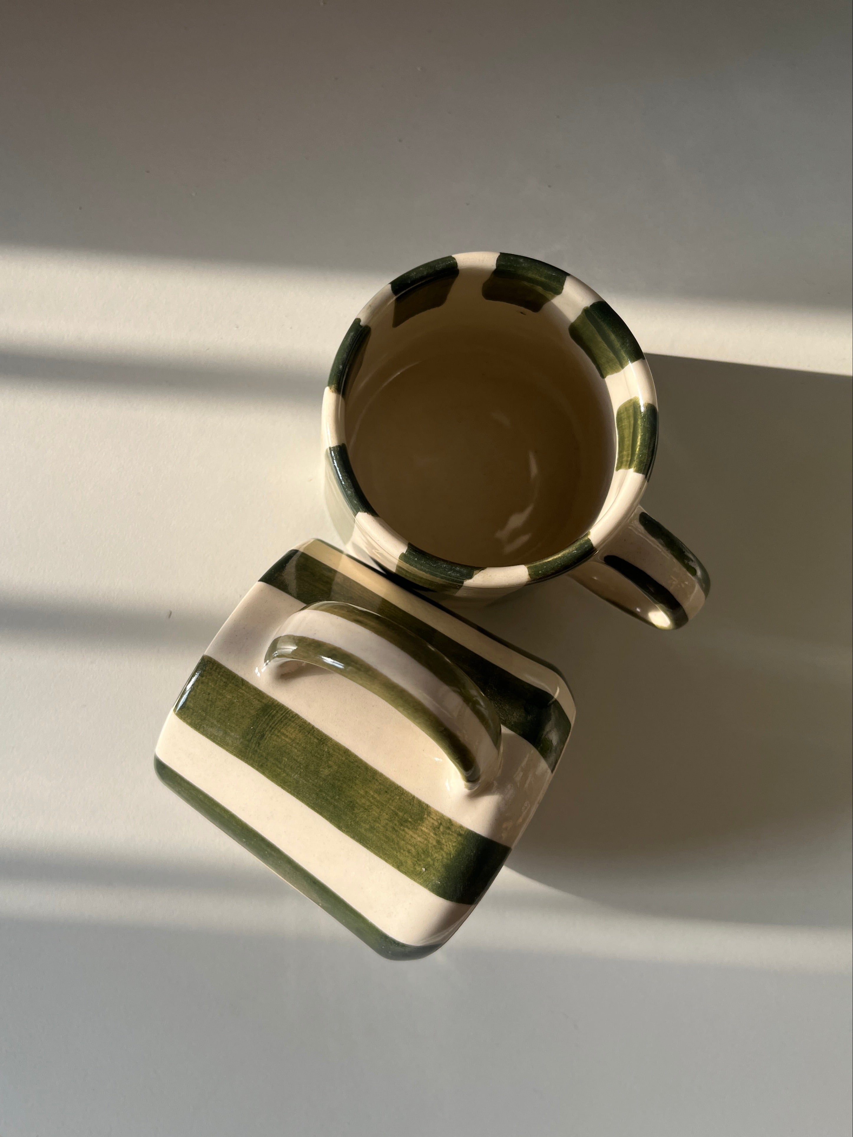 green stripes ceramic mugs on a reflective surface with a blurred background