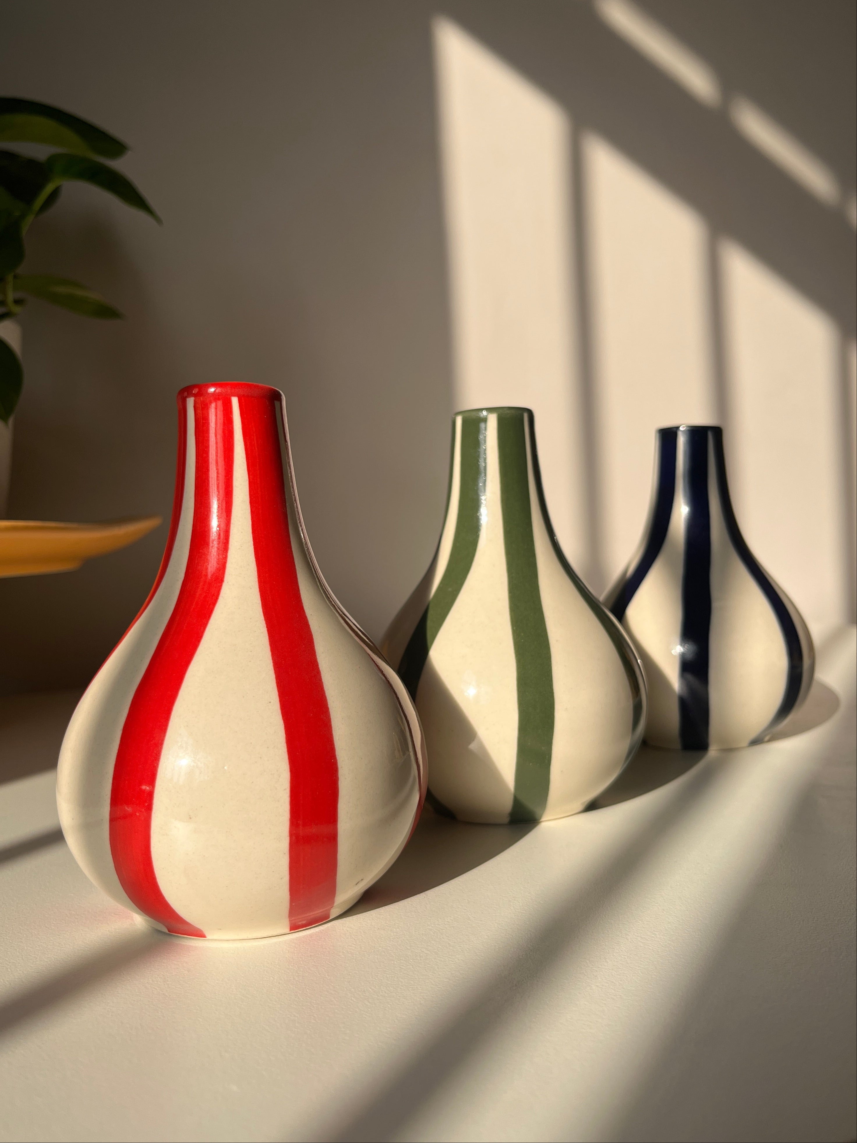 Three ceramic vases with striped patterns on a light background