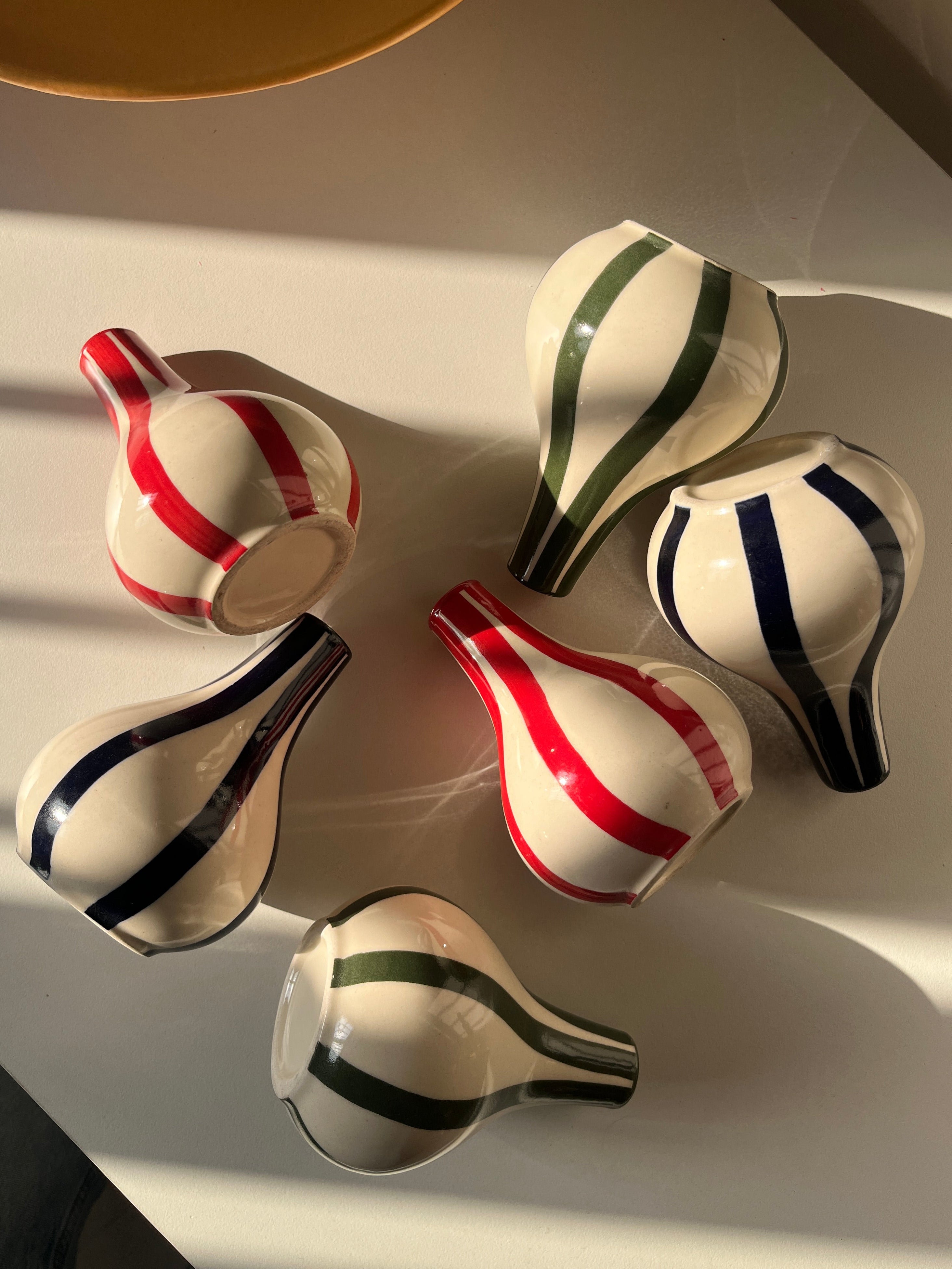 Set of ceramic vases with striped patterns on a white surface