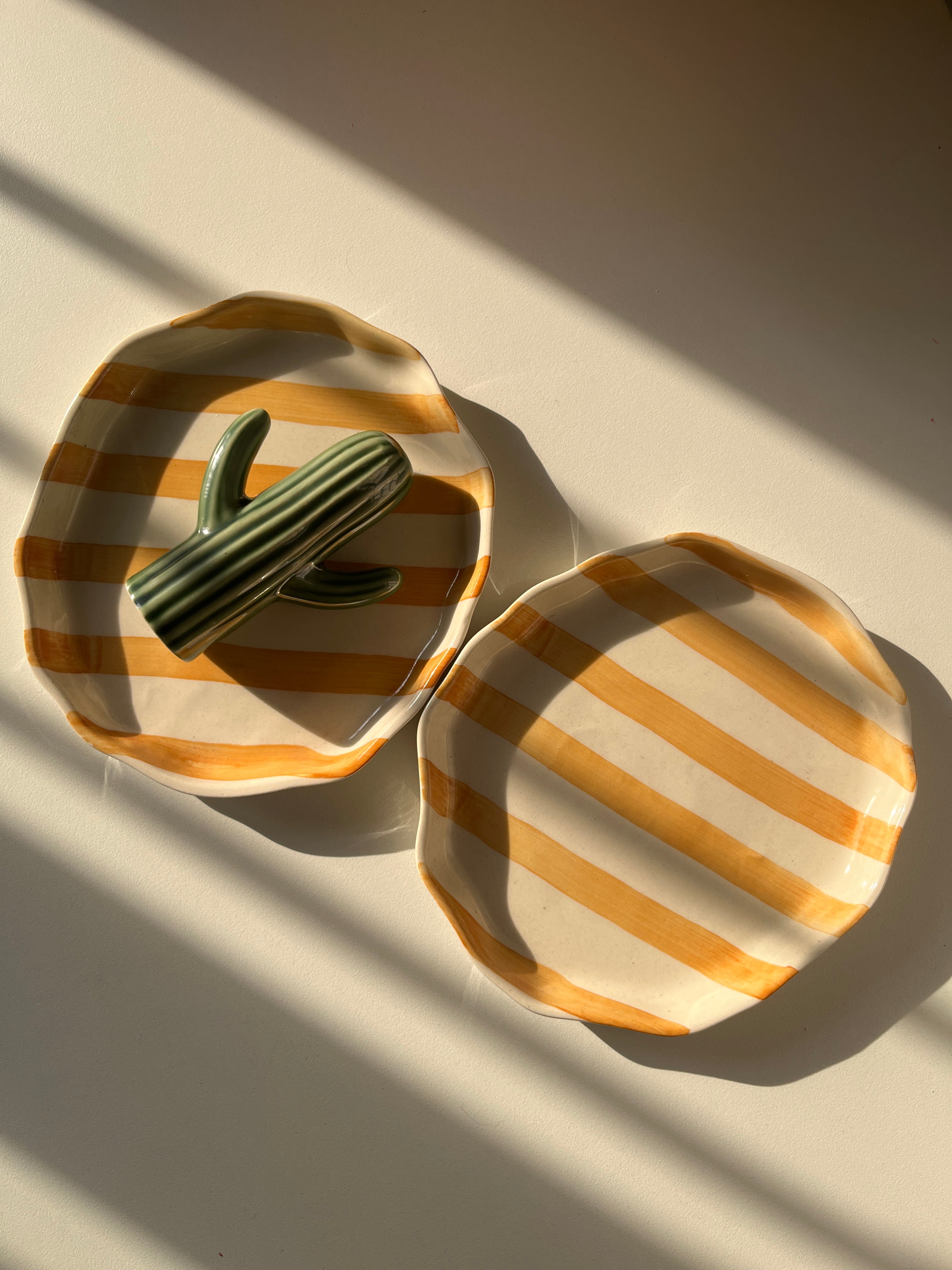 Decorative yellow ceramic tray with striped pattern, freeform shape