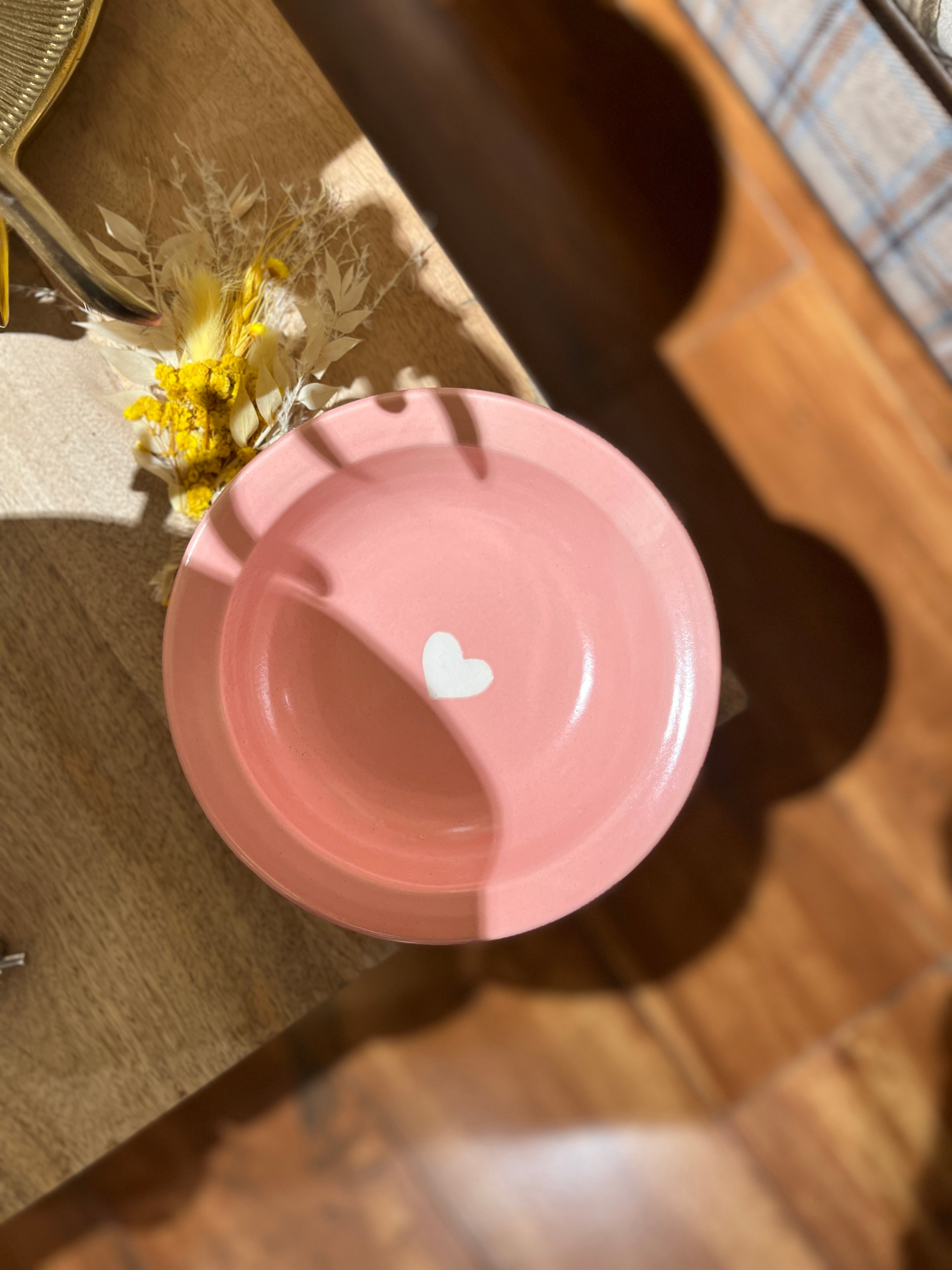 Pink plate with a white heart on a wooden surface