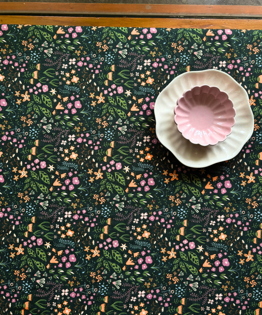 Decorative dining table cover with fantasy-inspired design with a pink daisy bowl and white plate on top