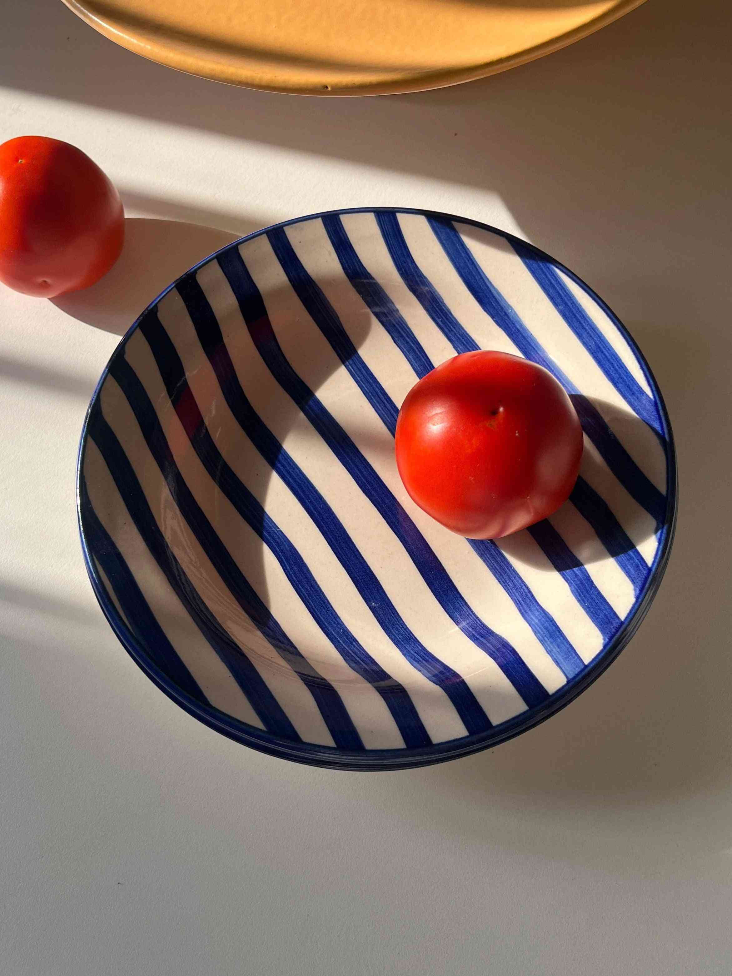 Ceramic pasta plate with bold blue stripes and glossy finish