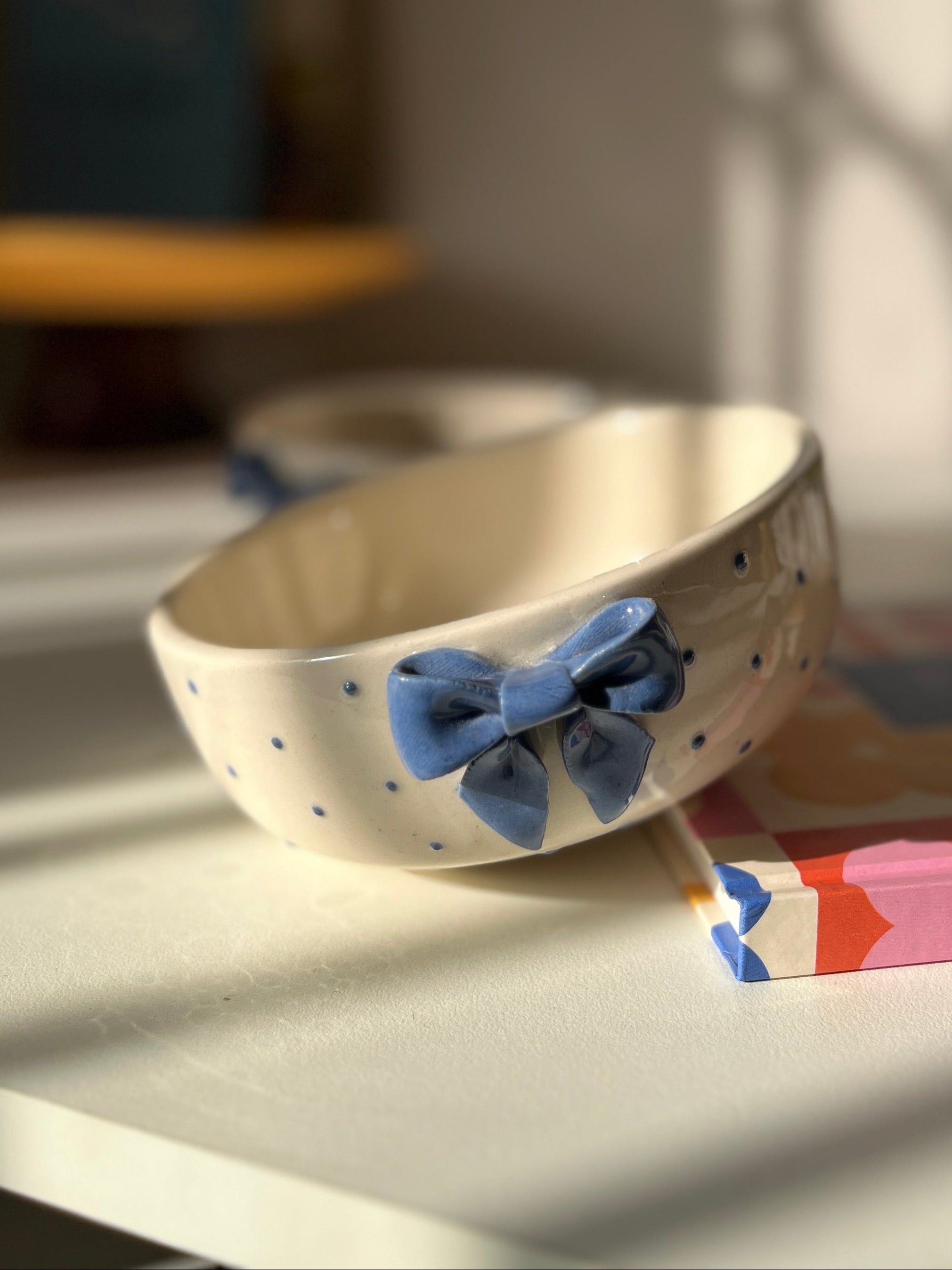 Ceramic bowl with a blue bow on a table with a blurred background