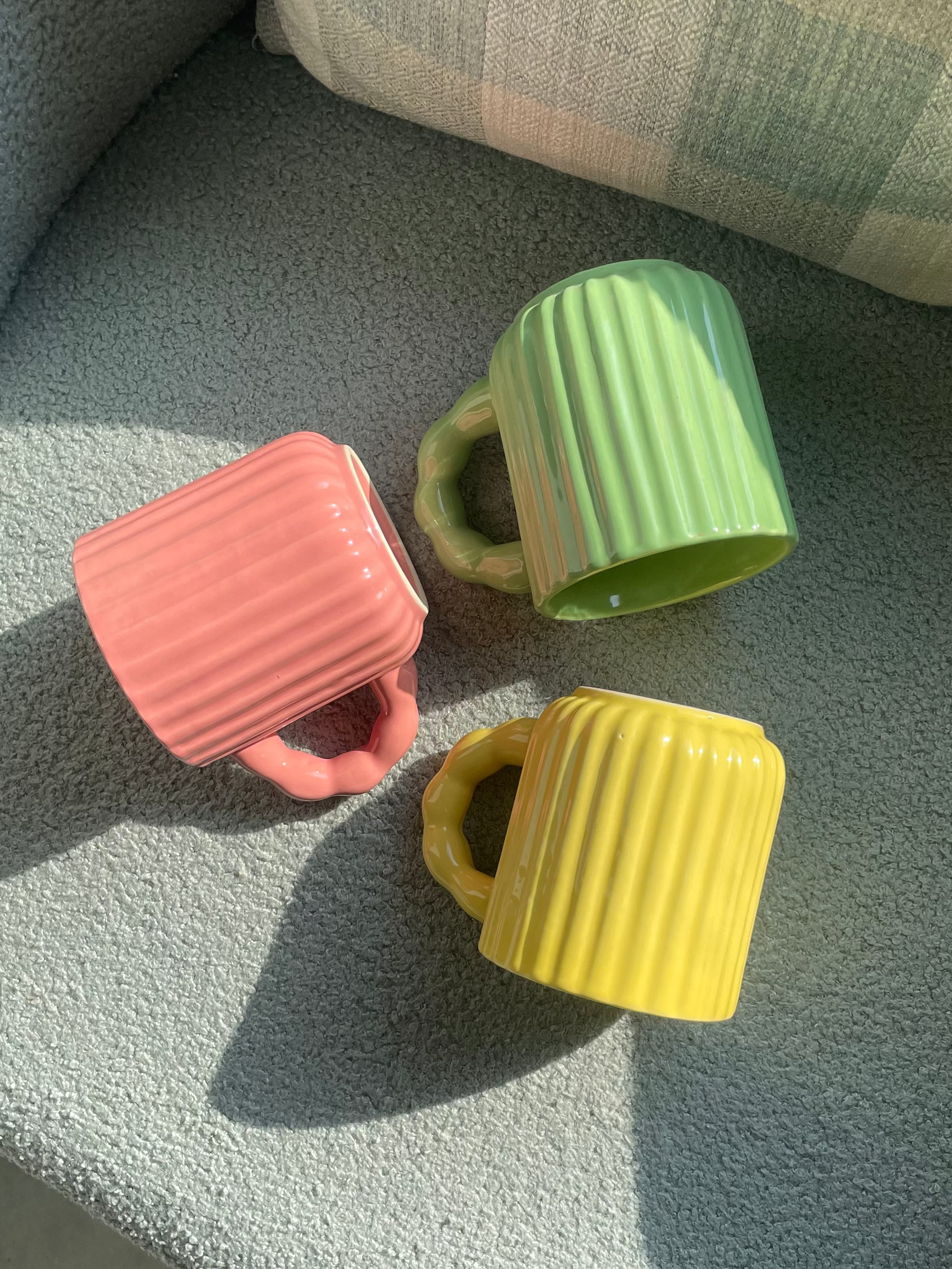 Close-up of the fluted texture and chunky handle design of ceramic mugs.
