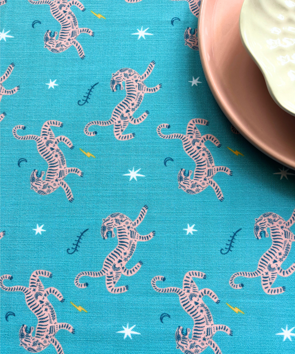 Blue fabric with pink tiger pattern and a plate on a blue background