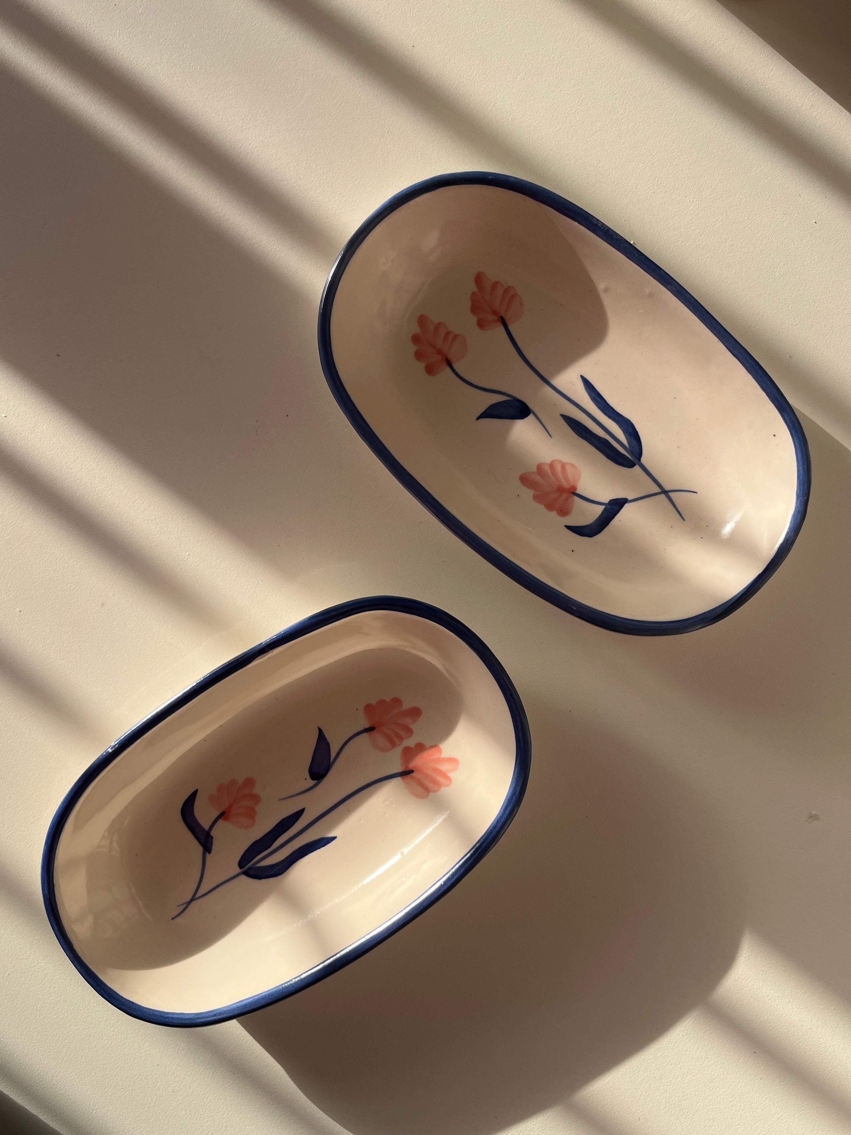 Two ceramic trays with floral designs on a white surface