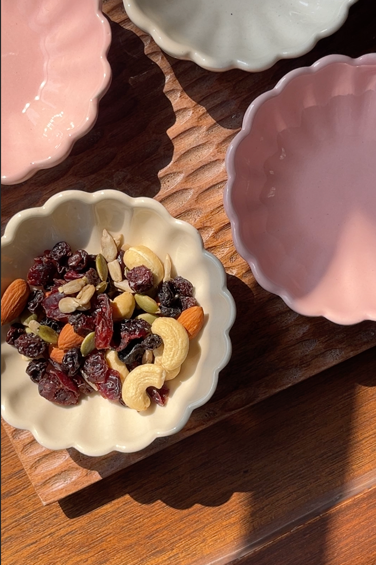 Daisy ceramic bowl available in soft pink and egg white with dried fruit under the sunlight