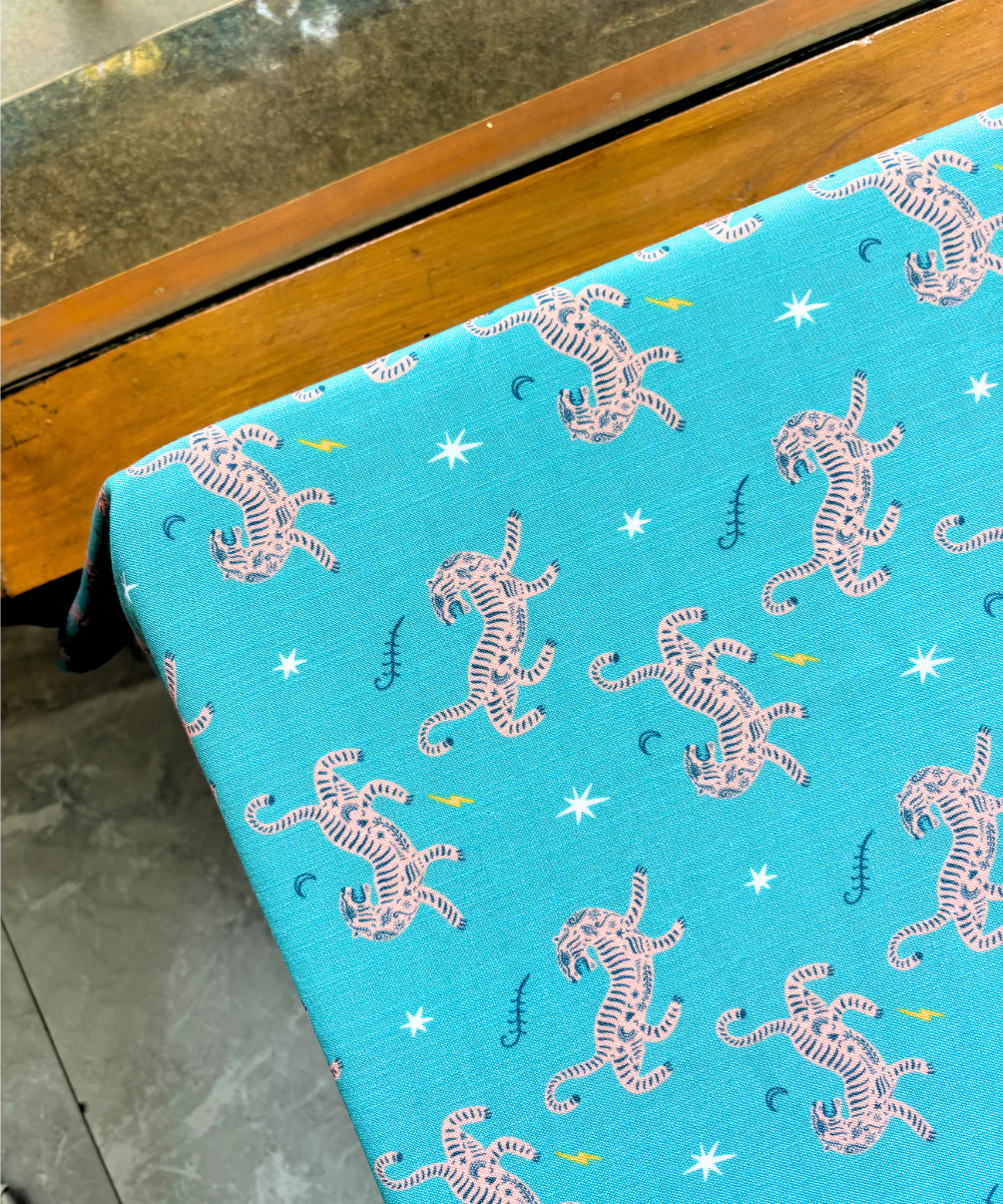 Blue slub linen tablecloth with white tiger pattern on a wooden table