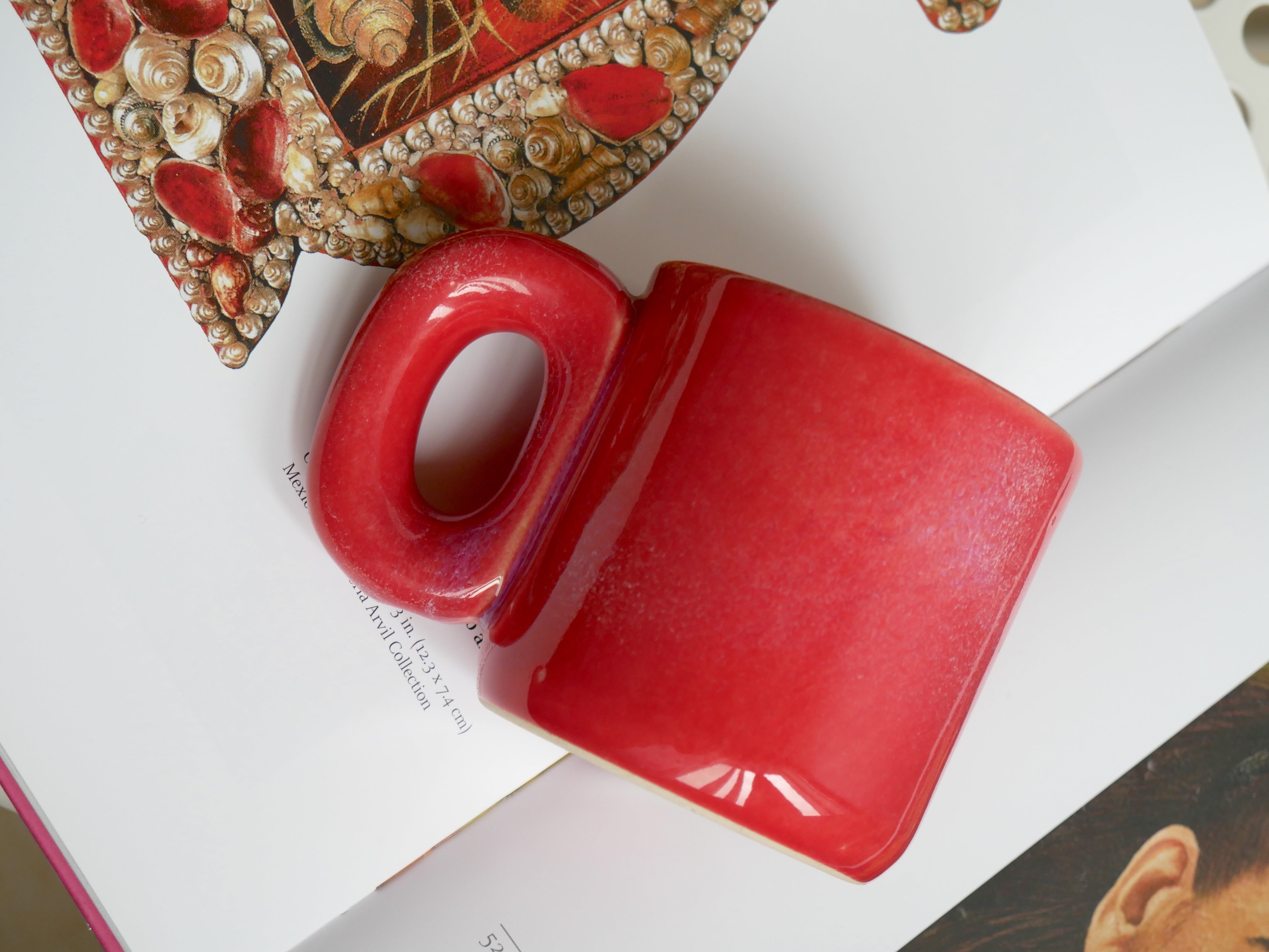 Red ceramic ember hug coffee mug on a book with decorative elements