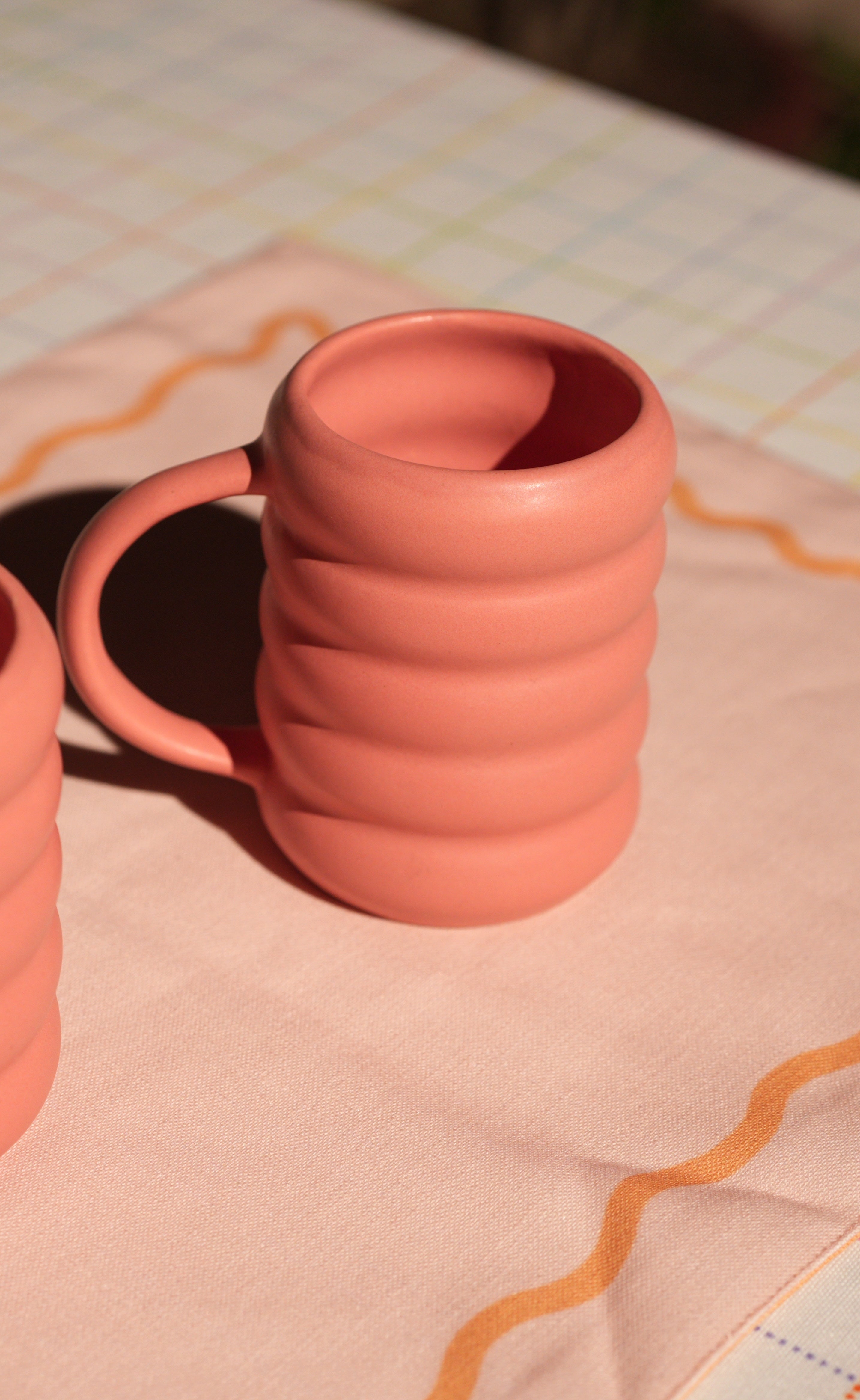 Two terracotta pink coffee bubble mugs on a checkered tablecloth