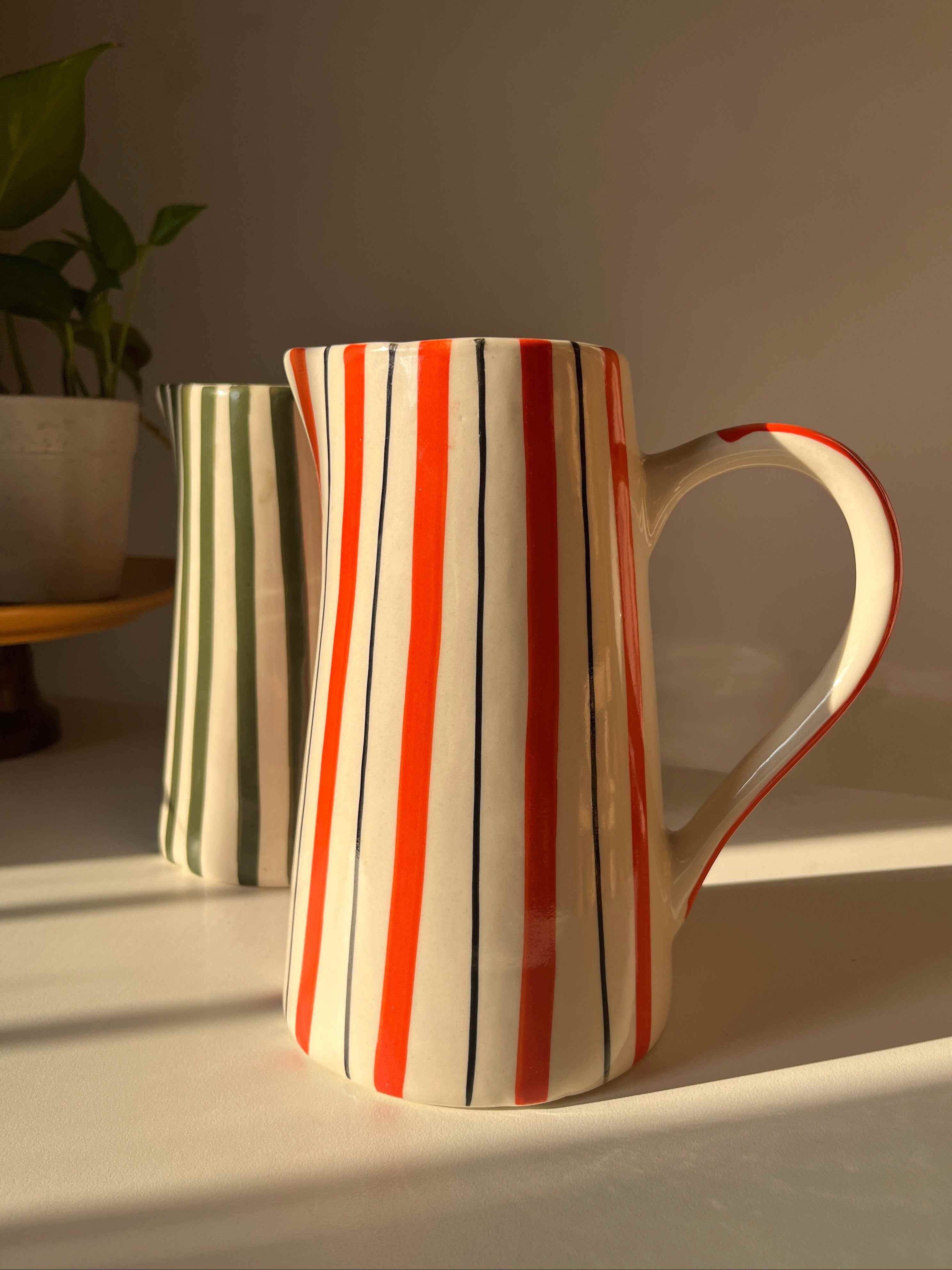 Hand-painted ceramic jug with orange stripes and curved handle
