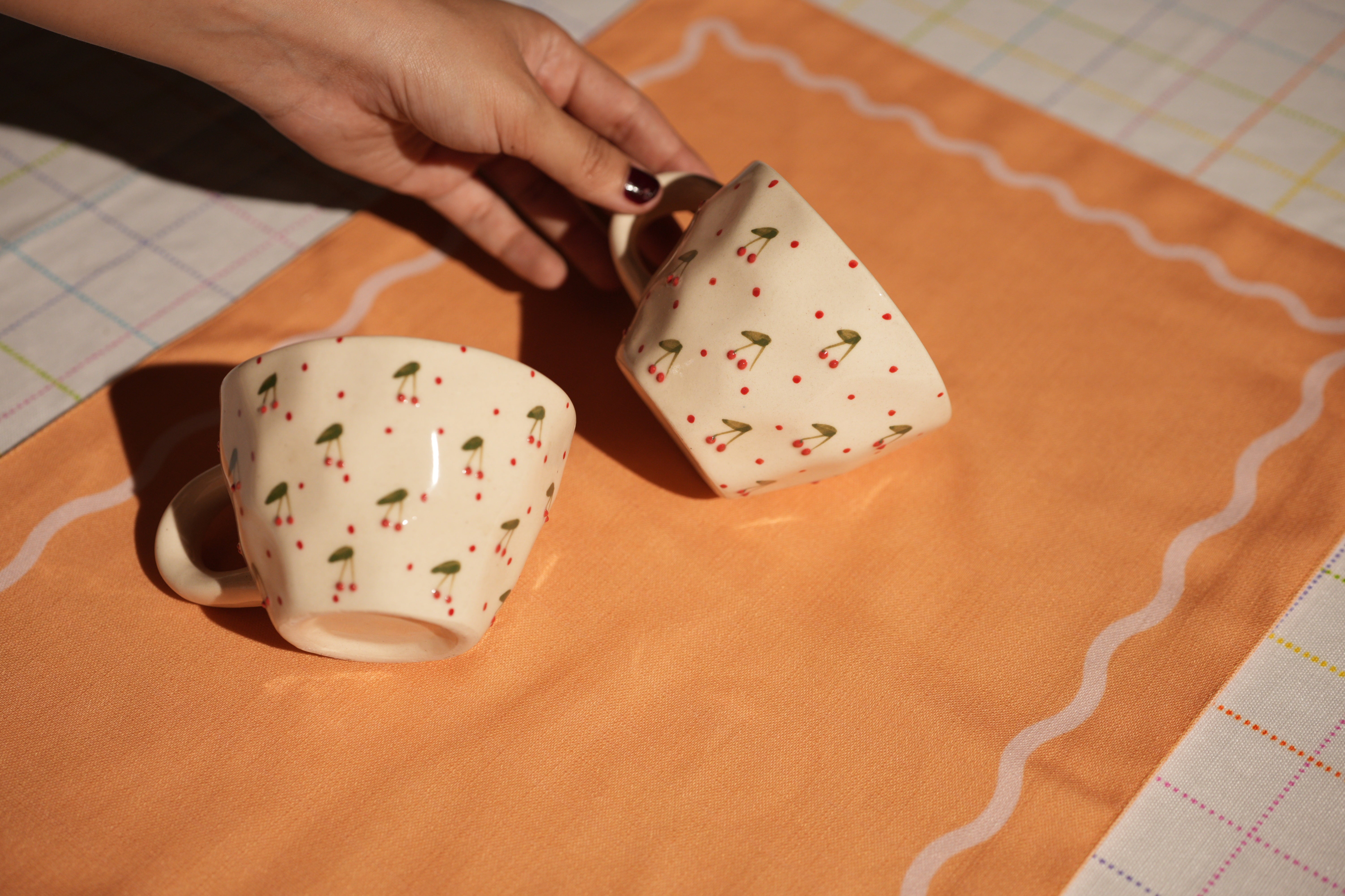 Close-up of cherry detailing on ceramic cups on madam jan linens