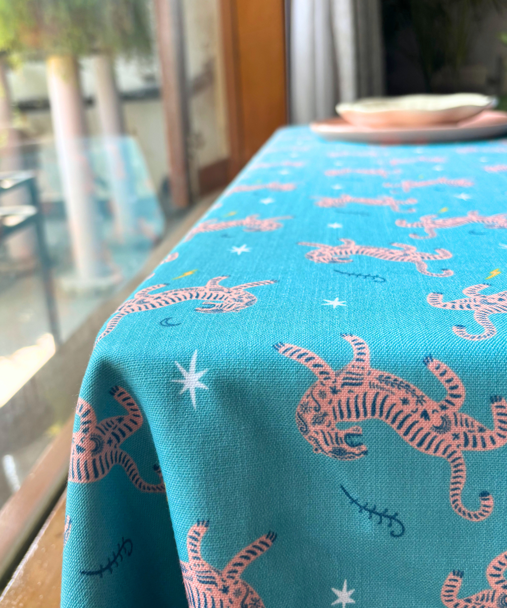 Teal tablecloth with pink tiger pattern on a table