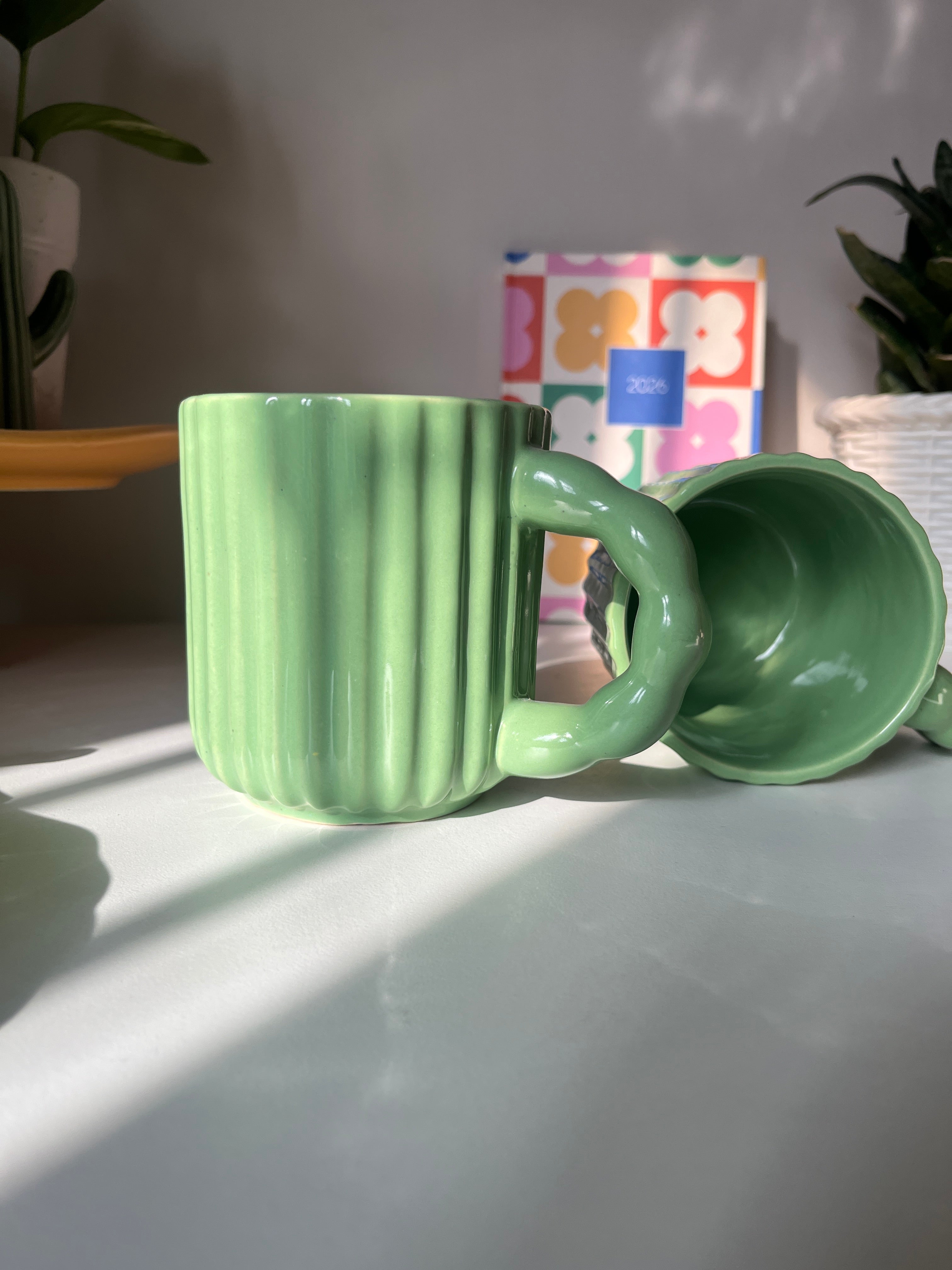 Close-up side view and top view of the ribbed ceramic texture and glossy green finish on the Kiwi Mug