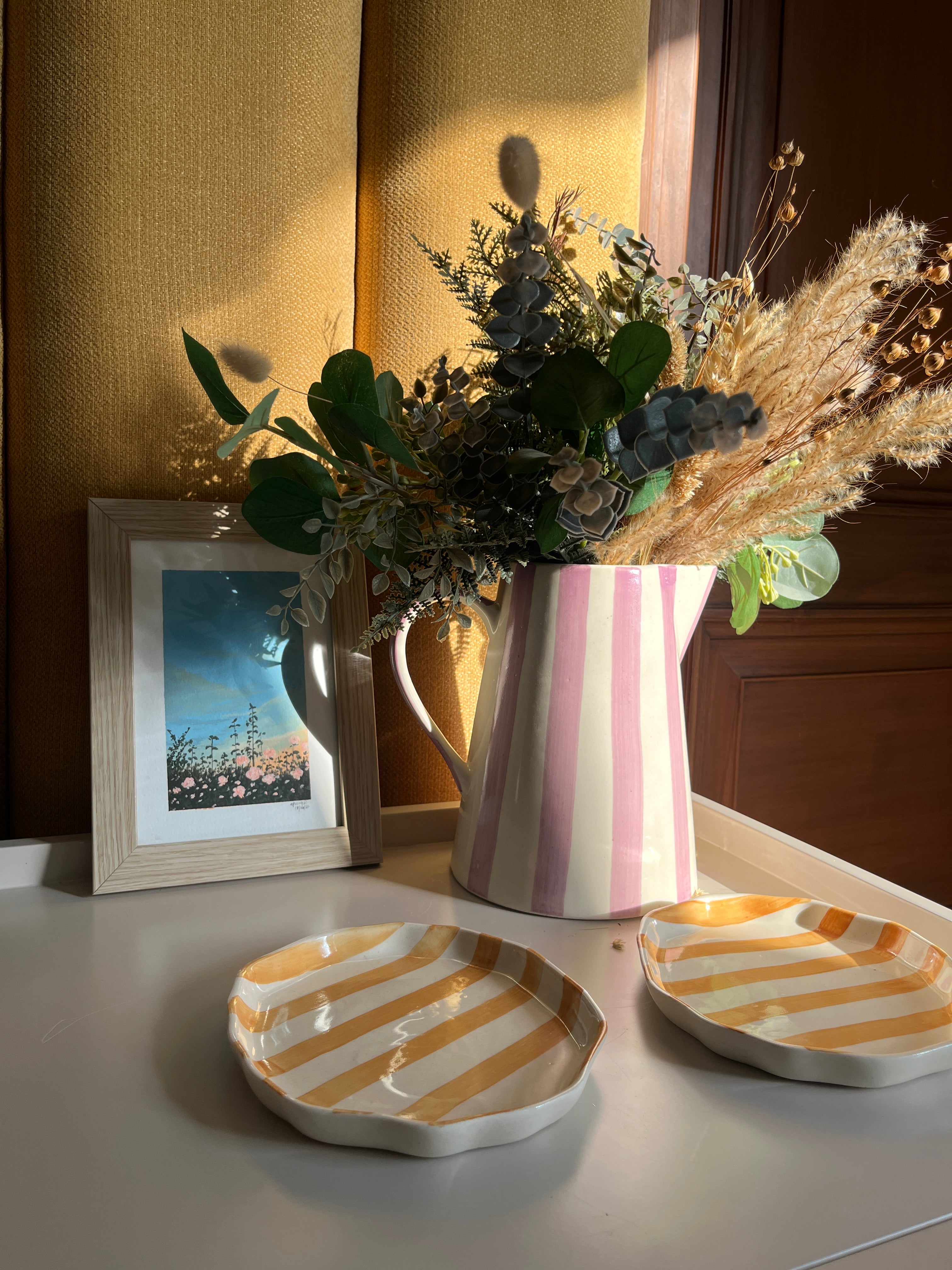 Purple and yellow ceramic tableware styled together on a bedside table.