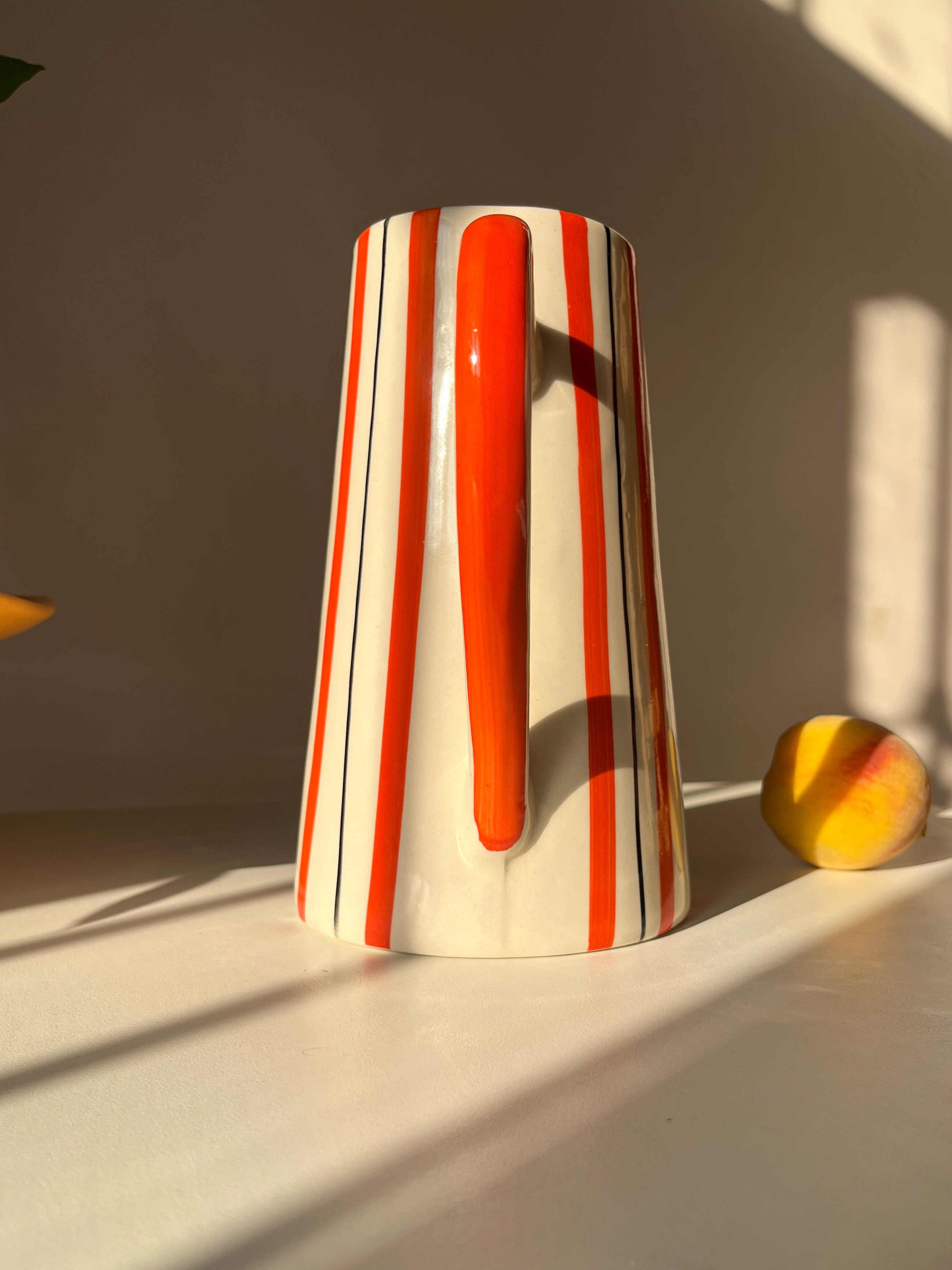 Tall ceramic jug vase with orange and fine dark line stripe detailing