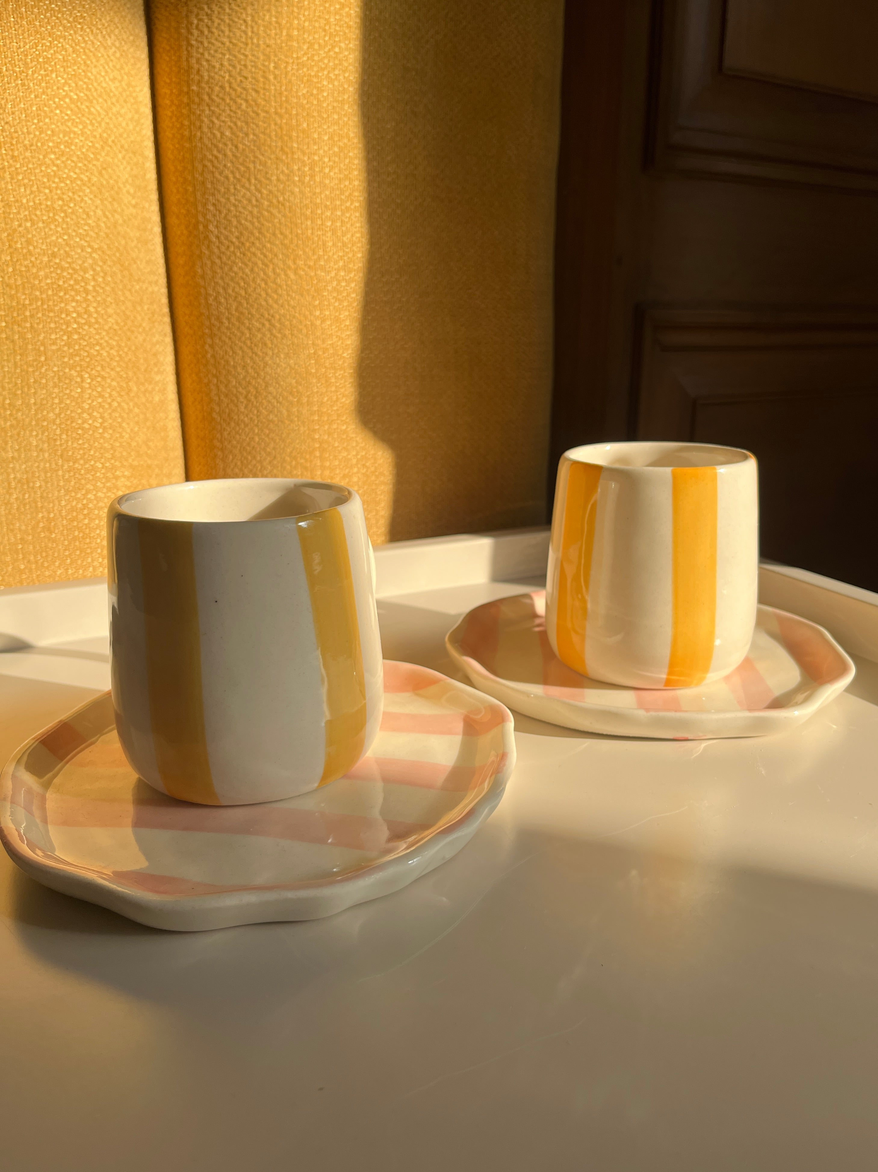 Yellow mugs and pink plates styled together for breakfast and coffee moments.