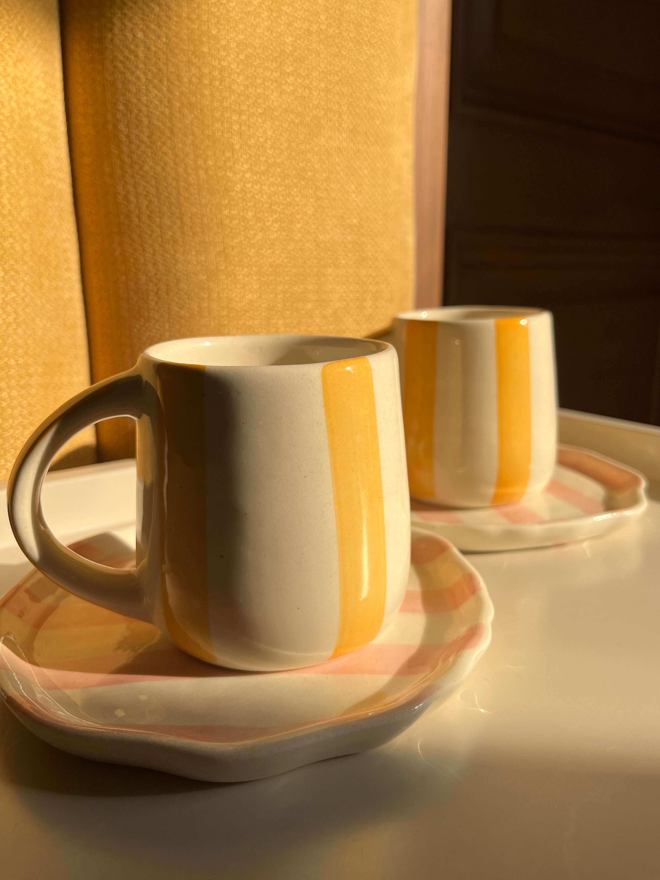 Taffy Time ceramic set featuring two yellow mugs and two pink plates.